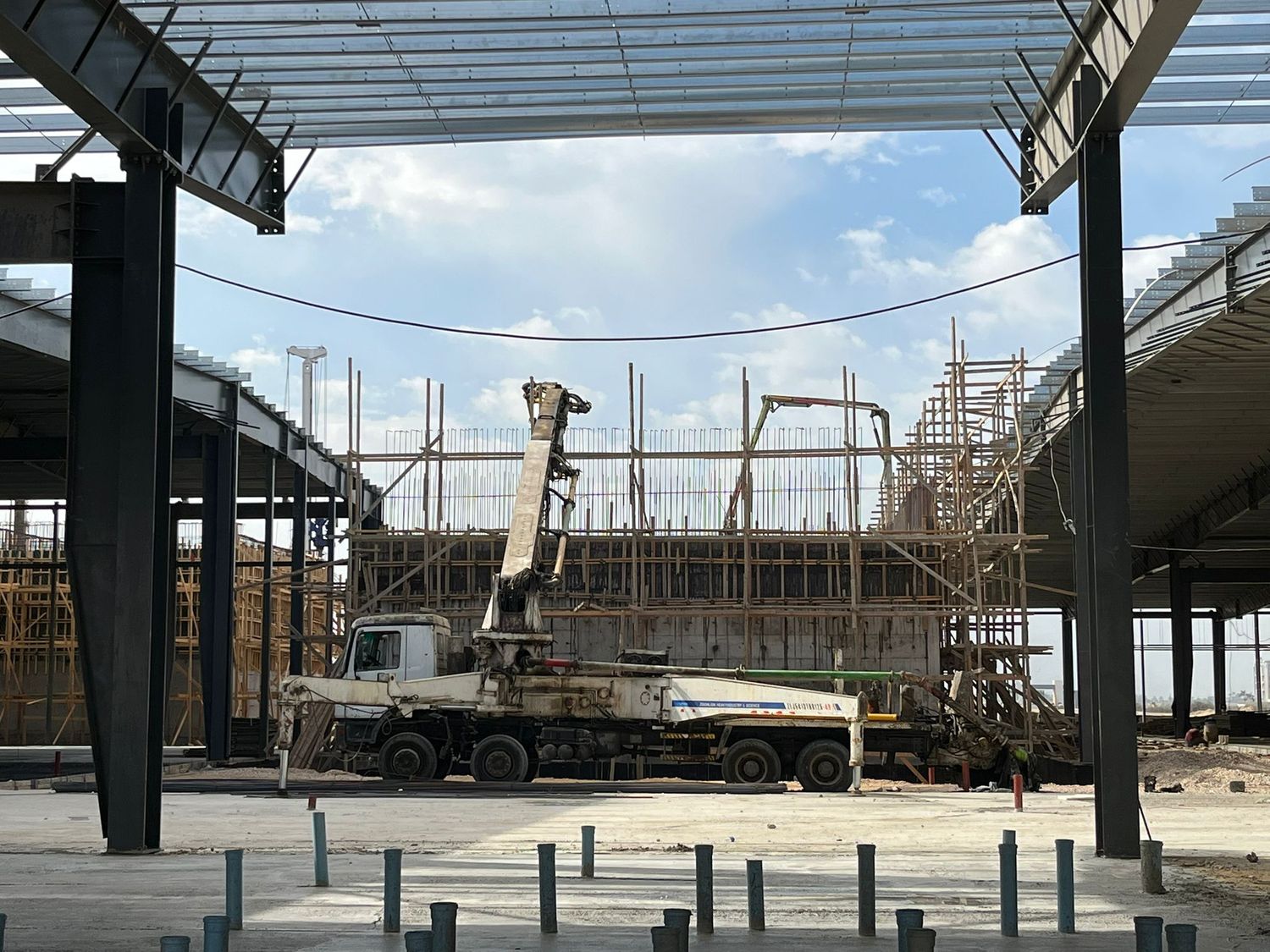 Industrial steel-frame construction project with concrete pump crew